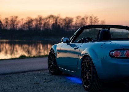 A sports car parked by a lake at sunset in Brzegi, Poland, offering a scenic view.