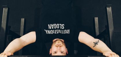 Bearded sportsman in t shirt with inscription exercising with weight while looking at camera
